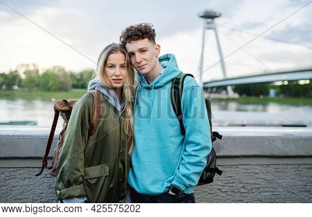 Happy Young Couple Travelers In City On Holiday, Looking At Camera.