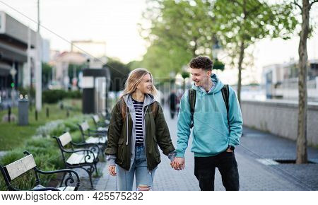 Happy Young Couple Travelers In City On Holiday, Walking And Talking.