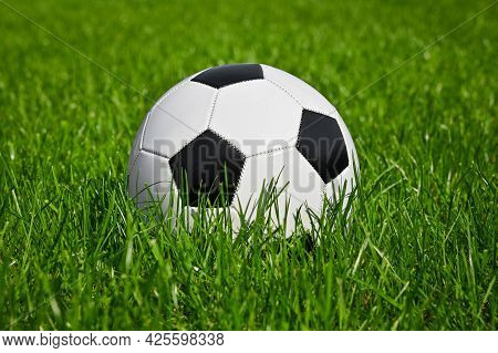 Close Up One Black And White Football Ball In Green Grass Of Soccer Turf Field Pitch, Low Angle, Sid