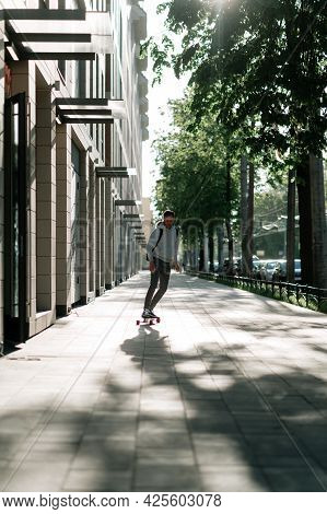 Young Casual Man On Longboard Riding City Street. Millennial Hipster Guy Student Longboarder Skatebo