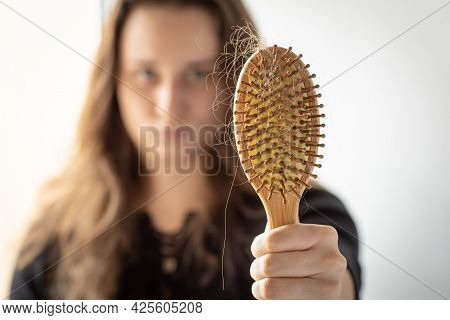 Young Woman Holding A Comb With A Lock Of Hair In Front Of Her, Focus On Comb, Hair Loss Problem, A 