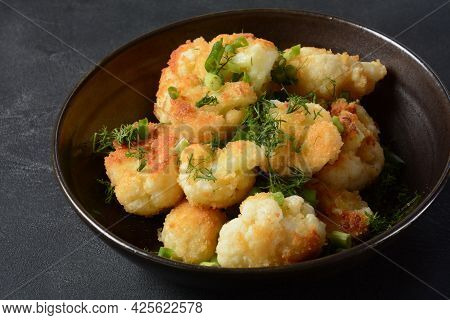 Fried Cauliflower Florets In Batter On A Black Plate. Coated Fried Cauliflower