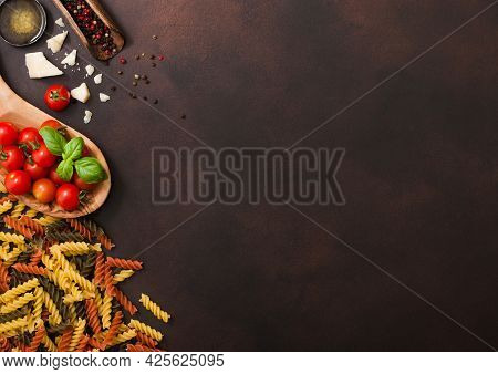 Fusilli Pasta With Cherry Tomatoes In Wooden Bowl With Pepper In Scoop And Parmesan Cheese With Salt