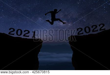 A Young Man Jump Between 2021 And 2022 Years Over Night Sky With Stars And Through On The Gap Of Hil
