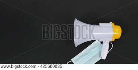 Megaphone And Face Mask On Black Background. Top Eye View And Nopeople.studio Shot.