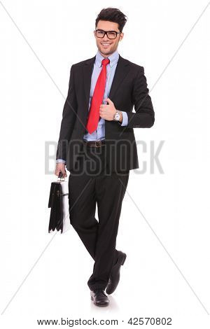 full length picture of a young business man walking forward with a briefcase and holding his suit jacket, while looking at the camera on white background