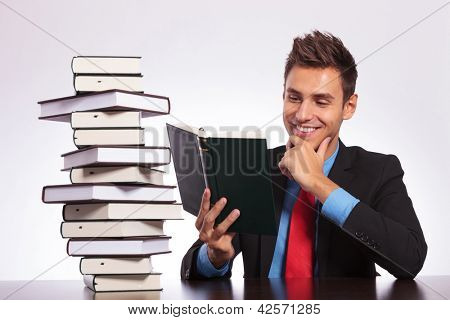 ชายหนุ่มธุรกิจที่สำนักงานจะอ่านหนังสือน่าสนใจจากกองของเขา ดีบนอินเตอร์