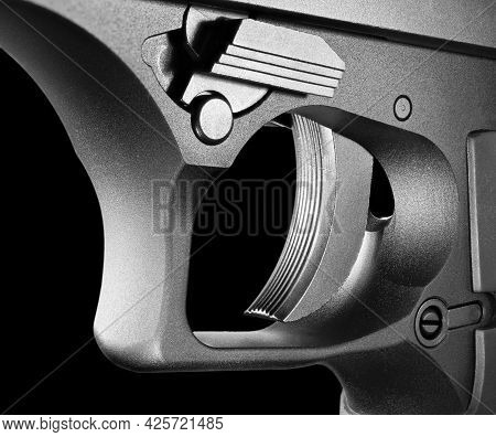 Trigger From A Large And Metal Semi-automatic Handgun That Is Up Close And With A Black Background.