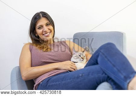 Portrait Of A Young Latina Woman Lying In A Blue Chair With Her Cat
