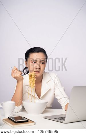 Asian Woman Working Hard Overtime Eating Instant Noodles At Office.