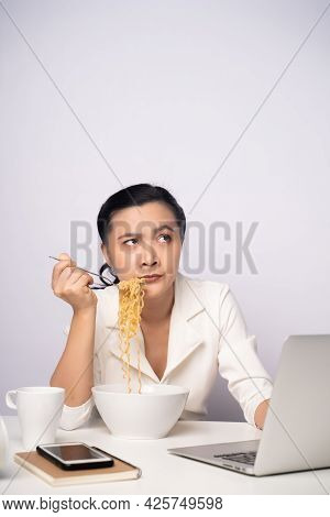 Asian Woman Working Hard Overtime Eating Instant Noodles At Office.