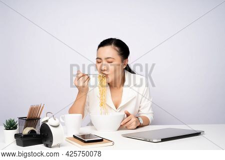 Asian Woman Eating Instant Noodles After Work Overtime At Office.