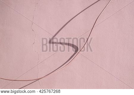 Wire And Shadow From It Against The Background Of A Wall With A Crack