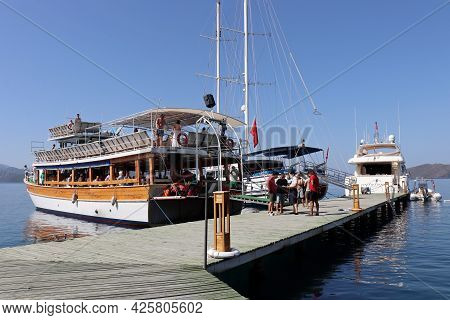 Hisaronu, Turkey​ -​ July 2021: Boat With Tourists Near The Wooden Pier In Aegean Sea. Summer Excurs