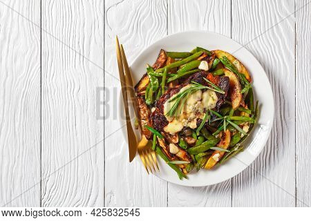 Pork Steak Topped With Melted Blue Cheese On A Pad Of Roasted Sugar Snap Peas, Potato Wedges, Green 