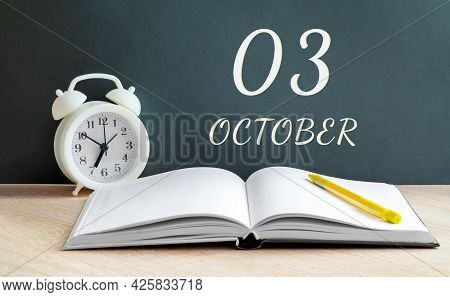 October 03. 03-th Day Of The Month, Calendar Date.a White Alarm Clock, An Open Notebook With Blank P