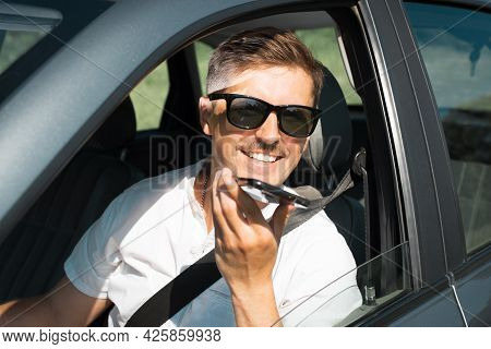 Attractive Young Man With Glasses Talking On A Speakerphone On A Cell Phone While Driving. Happy, Sm