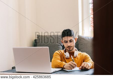 Young Adult Man In Yellow Clothes, Working From Home, Taking Stock Of Work And Family Life.concept W