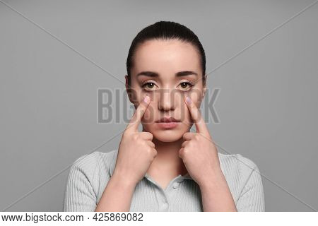 Woman Checking Her Health Condition On Grey Background. Yellow Eyes As Symptom Of Problems With Live