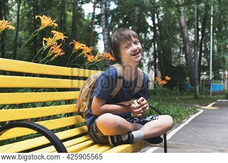 Happy Down Syndrome Young Boy With Backpack Ready For Going Back To School. Daily Life Child With Di