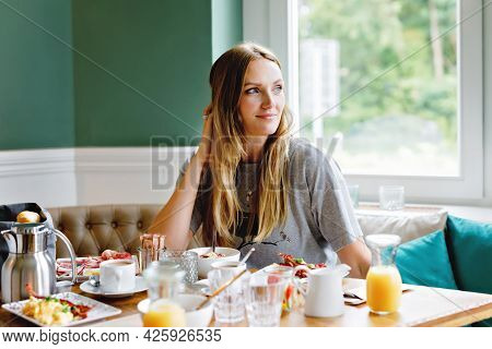 Young Confident Beautiful Woman Drinking Coffee And Having Breakfast. Happy Alone Woman In Indoor Ca
