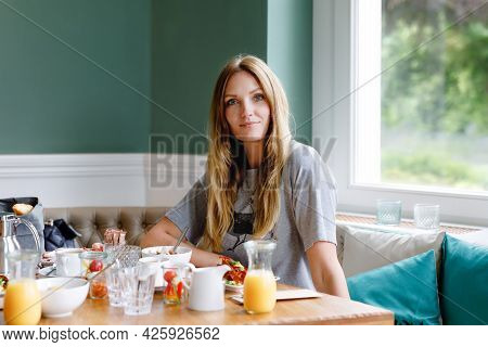 Young Confident Beautiful Woman Drinking Coffee And Having Breakfast. Happy Alone Woman In Indoor Ca