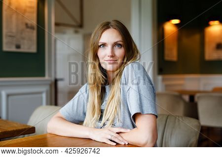 Young Confident Beautiful Woman Drinking Coffee And Having Breakfast. Happy Alone Woman In Indoor Ca
