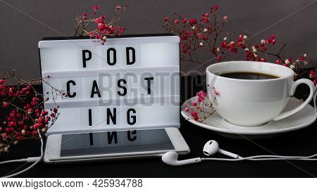 Podcasting Lettering. Headphones Mobile Phone. Dry Pink Flowers Decoration. Workplace. Black Coffee.