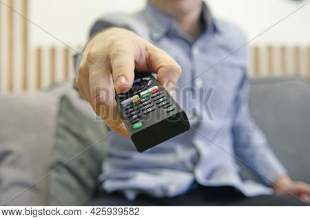 The Man With The Remote Control In Hand Watching The Sports Channel And Presses The Button On The Re