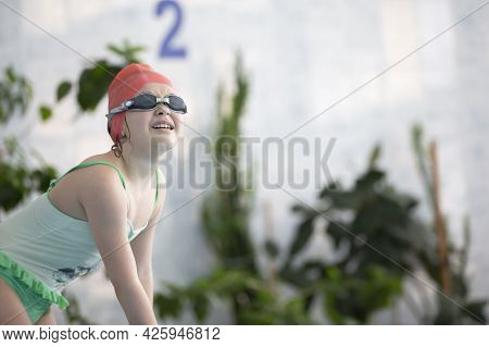 A Girl In A Swimsuit And A Swimming Cap With Glasses In The Sports Pool.