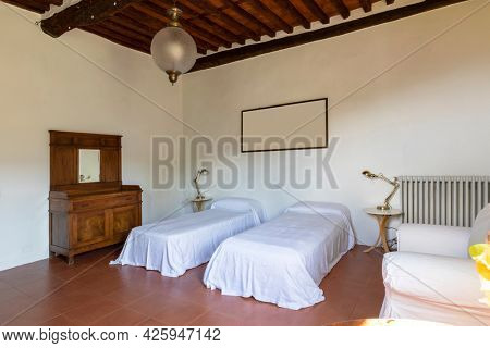 Interior of a bedroom with two single beds. Spartan ambiance and nothing luxurious. There are no people inside and the floors are red and beautiful.