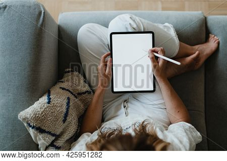 Woman using a stylus with a digital tablet during coronavirus quarantine at home
