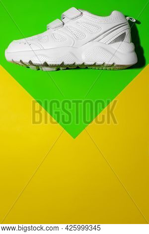 Top View One White Running Shoes On Top On A Geometric Paper Green And Yellow Background With Copy S