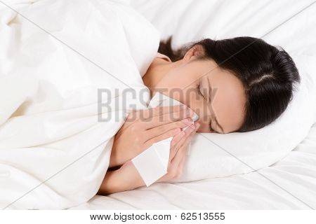 Sick Young Woman Blowing Her Nose On A Tissue
