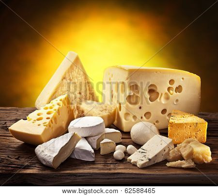 Different types of cheese over old wooden table.