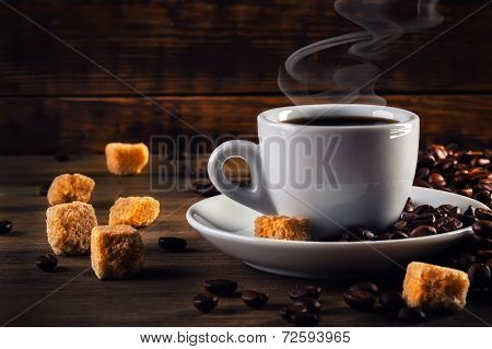 Cup of coffee in the old rustic style with cane sugar cubes and coffee beans.