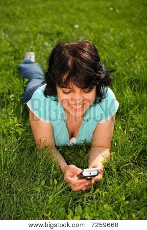 Mulher deitada no gramado usando Mobile