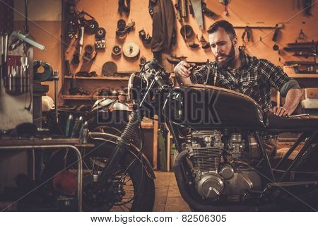 Mechanic building vintage style cafe-racer motorcycle  in custom garage