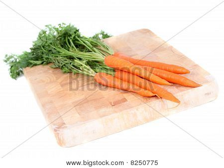 Carrots with leaves on wooden chopping board