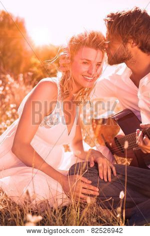 Handsome man serenading his girlfriend with guitar on a sunny day