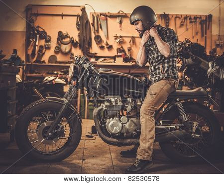 Rider and his vintage style cafe-racer motorcycle in customs garage 