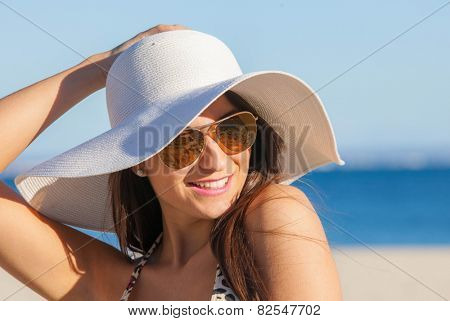 smiling summer woman on beach with sunglasses and floppy hat