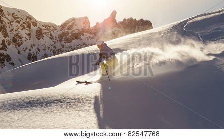 Male skier on downhill freerider with sun and mountain view