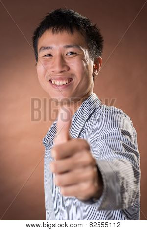 Young Chinese frank businessman give you an excellent gesture, closeup portrait in studio.