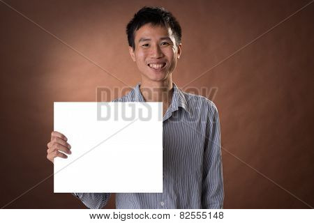 Young business guy of Chinese holding blank board in studio.