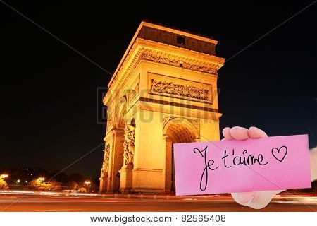 Composite image of hand holding card showing je taime against arc de triomph