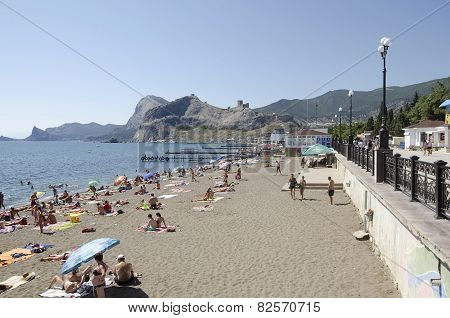 People Sunbathe And Swim On The Beach In Sudak In The Crimea