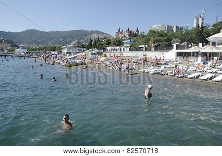 People Sunbathe And Swim On The Beach In Sudak In The Crimea
