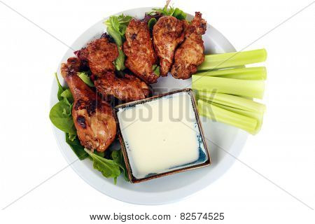 Buffalo Chicken Wings with Celery and Blue Cheese Dressing and Lettuce on a White Plate isolated on white with room for your text. Buffalo Wings are enjoyed by millions of people around the world.