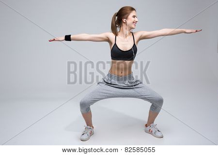 Smiling woman doing stretching excersises over gray background